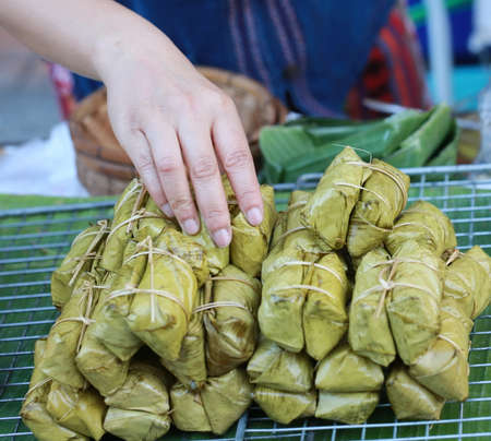 hand with Thai sweet in banana leave package steamed, foodの写真素材