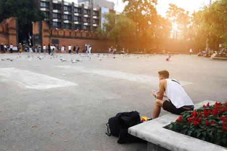 The tourist man with travel bag at Tha Pae Gate, History fortress gate, Chiang Mai ,Thailand on December 18,2017 in Chiangmai,Thailand. Handsome man sit waiting on benchの写真素材