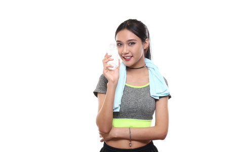 Charming tan skin Asian woman with exercise suit hand hold pure water bottle isolated on white background, Presenting fitness and good healthyの写真素材