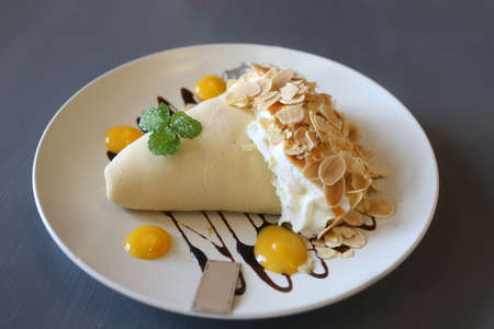 mix fruit , ice cream and sweet crepe with whip cream and syrup on white plate backgroundの写真素材