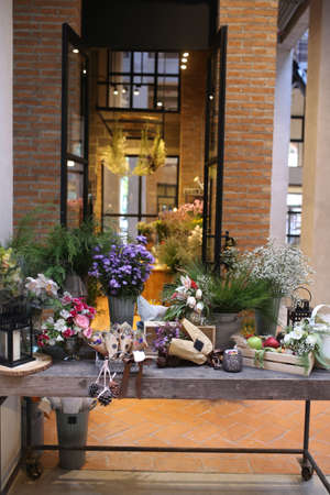 entrance into flower shop block wall building and steel door in market , romantic pink lily flower in metal vase pot with plastic paper cover background , export colorful floral businessの写真素材