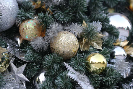 gold color Christmas ball hang on green pine tree with blurred night light new year party background.の写真素材