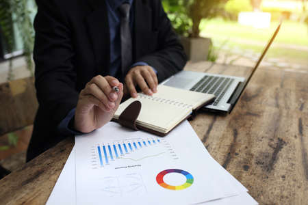banker businessman people group working with laptop and financial document chart on wood table together.の写真素材