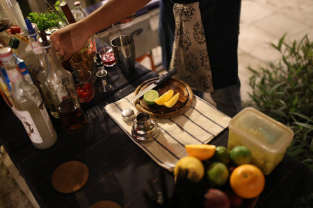 shaker making colorful cocktail beverage from orange and lemon juice on wood table at night. Pub and restaurant travelの写真素材