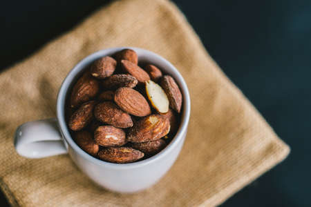 Closeup Salt Roasted Almond in white cup on a Sack.の写真素材