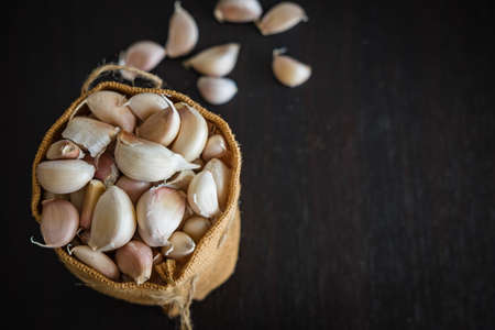 Fresh garlic in sack on wood tableの写真素材