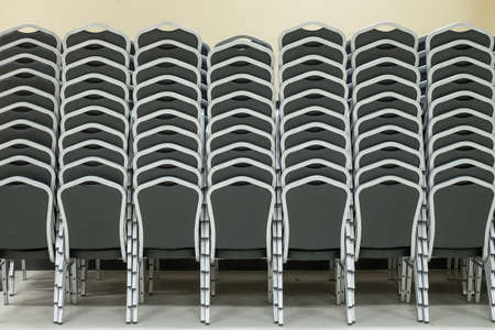 Stacked rows of black chairs in meeting roomの写真素材