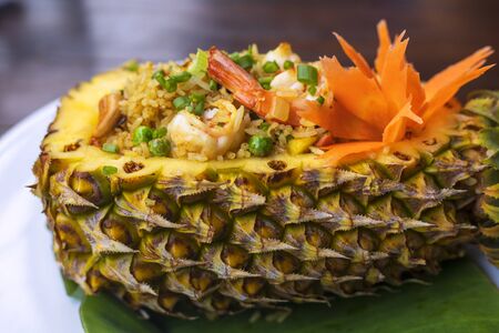 Close up Thai royal pineapple fried rice. Fried rice with shrimps served in a pineapple on wood table.の写真素材