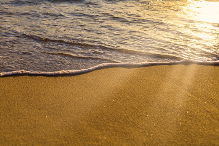 Soft wave from sea come to wet sand beach and sun ray background. With copy space for text or design. Beach background.の写真素材