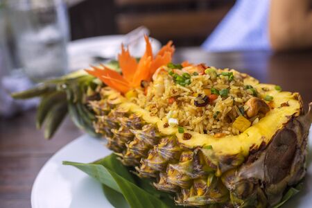 Thai royal pineapple fried rice. Fried rice with shrimps served in a pineapple on wood table.の写真素材