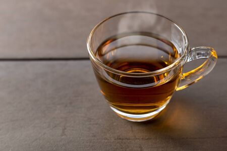 Close up hot tea cup on wood table . hot tea in handle glass with copy space for text or design.の写真素材