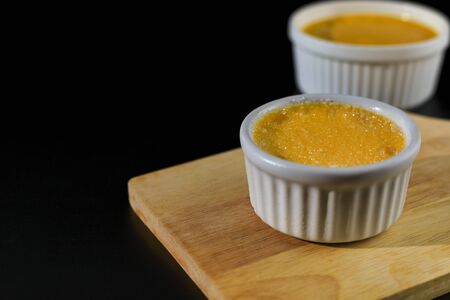 Close up homemade creme brulee in white ramekin  with sugar top up on black background with copy space. French dessert creme bruleeの写真素材