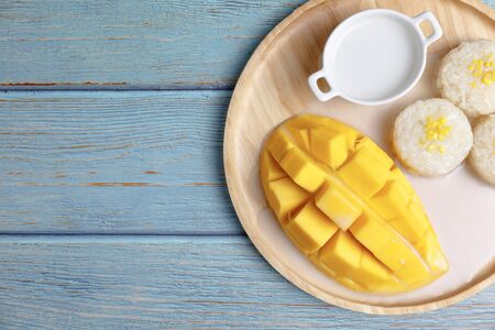 Top view Fresh yellow mango peel and Sliced cubes with sticky rice ,coconut milk on wood plate . Tropical fruit. Thai dessert. Dessert fruit. summer concept.の写真素材