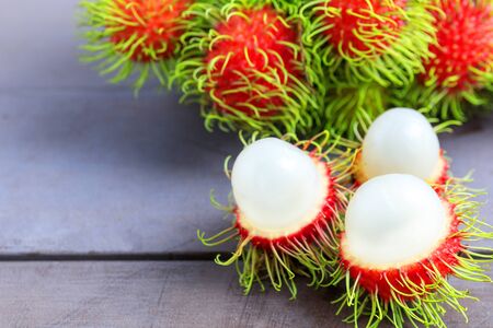 Fresh rambutan peeled on wood table with bunch of fresh ripe rambutan background. Tropical fruit fresh rambutan peeledの写真素材