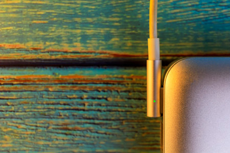 Top view close up laptop with electric charger cable on blue  color wooden table with copy space.