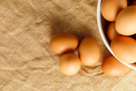 Top view fresh chicken eggs and blur fresh chicken eggs in white bowl on linen tablecloth with copy...