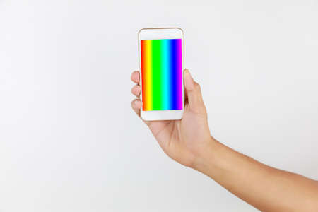 Hand man holding mobile phone in screen show LGBT symbols. Hand hold smart phone with rainbow screen isolated on white background with copy space. LGBT Concept activism, community and freedom. Lesbian, gay, bisexual and transgender.の写真素材
