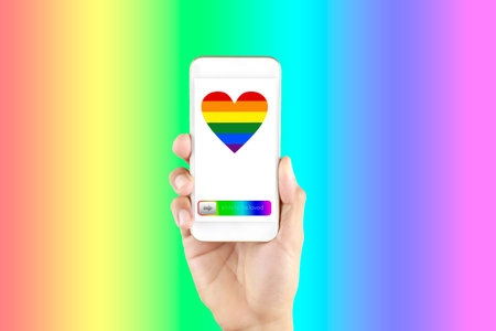 Hand man holding smart phone in screen show LGBT symbols. Hand hold phone with rainbow heart screen...