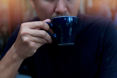 Close up hand man holding coffee cup in the cafe, Man relax with coffee coffee after work business drinking concept.の写真素材
