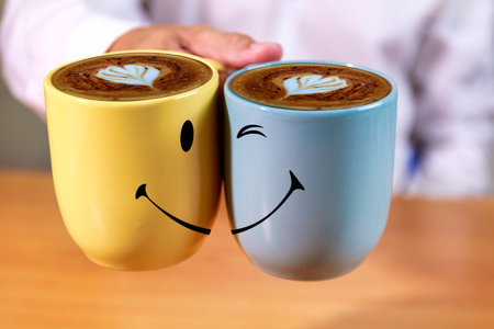 Close up Hand businessman hold coffee cups with smle face background. Hand man hold yellow and blue...