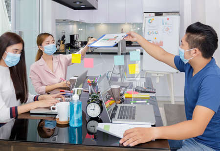 Asian Business Team Meeting Brainstorming Business start up working at Private Home Office social distancing among Coronavirus outbreak New generation business people meeting analysis work from laptopの写真素材