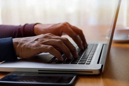 Close up businessman using laptop computer at home. Close up male hands typing on laptop keyboard in...