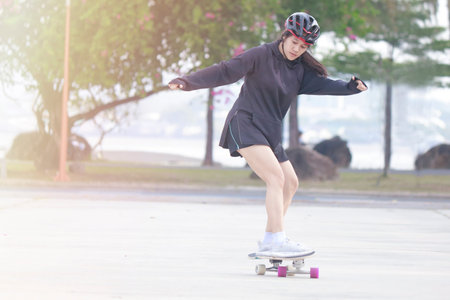 Asian women on skates board outdoors on beautiful summer day. Happy young women play surfskate at...