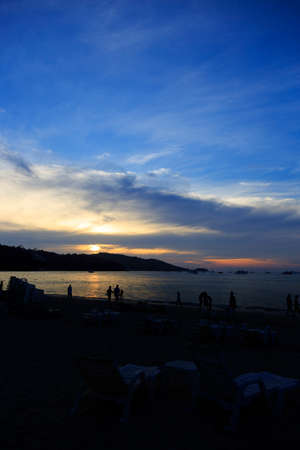 Silhouettes of group of people during the sunset in Seaside beach. Beautiful sunset over the sea with silhouettes happy group of people relax. Holiday and summer conceptの写真素材