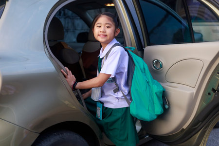 Asian School girl Wear school uniform And carrying a green backpack Getting on the bus to go to school in the morning. Happy primary school child get in car. Family in car transportation concept.の写真素材