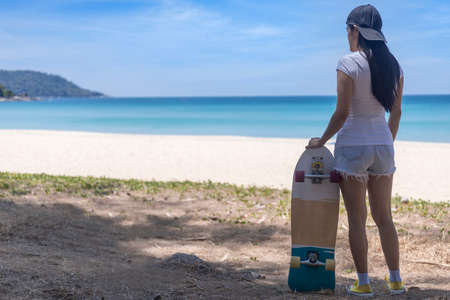 Young women hold surf skate board with beach background. Women stand with surf skate relax and enjoy with tropical beach with copy spaceの写真素材