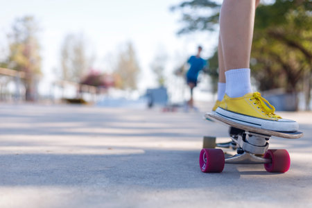Close-up and motion movement Asian women surf skate or skateboard outdoors on beautiful morning. Happy young women play surf skate at park on morning time. Close up Asian women leg wear sneaker paly surf skate on public park. Sport conceptの写真素材