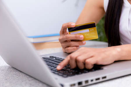 Young woman holding credit card and using laptop computer. Women working at home. Online shopping, e-commerce, internet banking, spending money, working from home concept. Technology shopping online concept.の写真素材