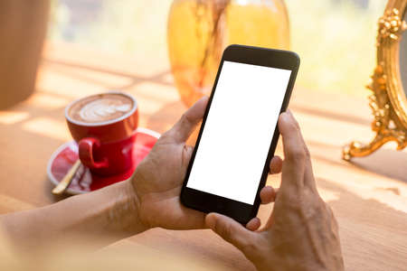 Close up hands of beautiful young woman holding mobile, smart phone sitting in cafe. Soft focus hands of women holding and use cell phone in coffee shop. Tectechnology and lifestyle concept.の写真素材
