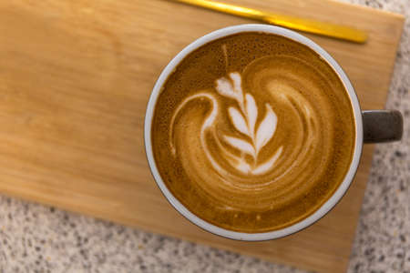 Soft focus Top view close up of hot espresso, latte coffee in a red ceramic cup on blur wood table background.の写真素材