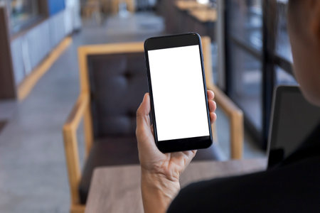 Close up hands of woman using mobile phone, cell phone in coffee shop. Hands of women holding blank...