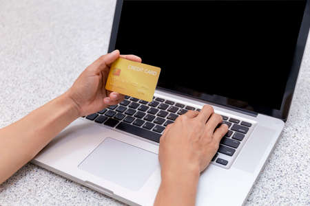 Young woman holding credit card and using laptop computer. Women working at home. Online shopping, e-commerce, internet banking, spending money, working from home concept. Technology shopping online concept.の写真素材