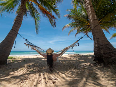 Phuket Thailand. Asian young woman relaxing on hammock by the beach at sunset. Young attractive female swinging on hammock. Holiday vacation summerの写真素材