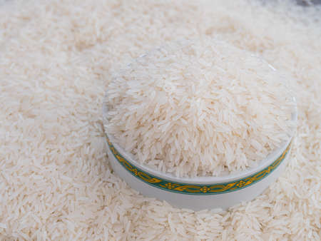 Rice in a white bowl and scattered near on wooden table with copy space for text and designの写真素材