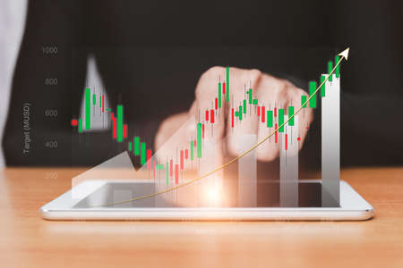 stock market growth up. Businessman holds tablet and displays holographic graph showing statistics of profitable graphs. Ideas of growth planning and business strategies to see trends in good businessの写真素材