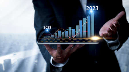 Hand of businessman holding tablet analysis stock market graph growth and increase of chart positive indicators. Hand holding tablet show stock chart on light gray background. copy space bannerの写真素材