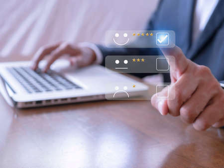 Businessman touching the virtual screen check mark joyful Smile face icon to give happiness in service. Customer service and satisfaction concept. Very impressed with the rating.の写真素材
