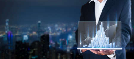 Hand of businessman holding tablet analysis stock market graph growth and increase of chart positive indicators. Hand holding tablet show stock chart on light gray background. copy space bannerの写真素材
