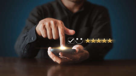 Businessman touching the virtual screen check mark joyful Smile face icon to give happiness in service. Customer service and satisfaction concept. Very impressed with the rating.の写真素材