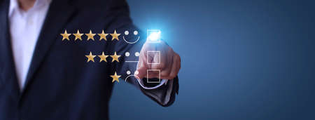 Businessman touching the virtual screen check mark joyful Smile face icon to give happiness in service. Customer service and satisfaction concept. Very impressed with the rating. With copy space bannerの写真素材