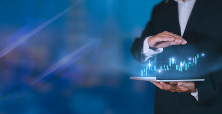 Hand of businessman holding tablet analysis stock market graph growth and increase of chart positive...