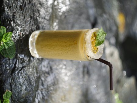 fruit juice, fruit smoothie, fruit juice, fruit juice in glass Placed on a rock near the waterfall.の写真素材
