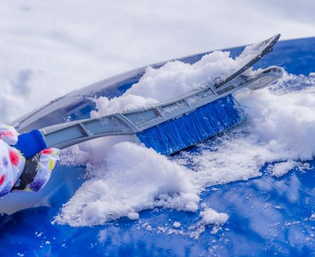 Removal snow from car body with brushの写真素材