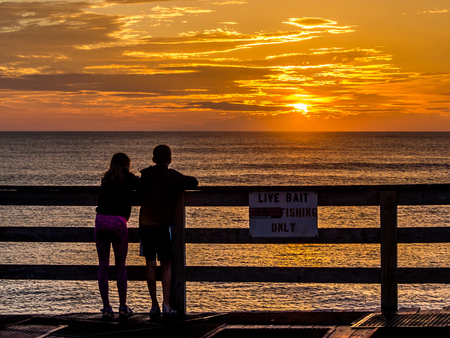 Kids looking at ocean sunrise from the pier at Avon, NCの写真素材