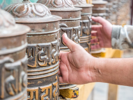 People touch prayer wheels in the buddhist temple 