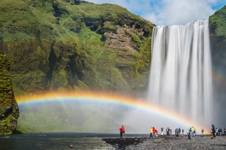 Tourist crowd at sunny summer day at Skogafoss waterfall in Icelandの写真素材
